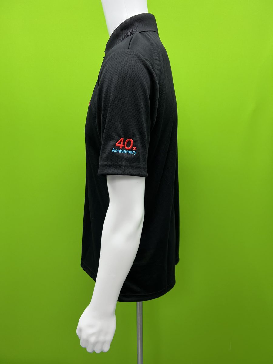 Black corporate polo with embroidered anniversary logo on the sleeve